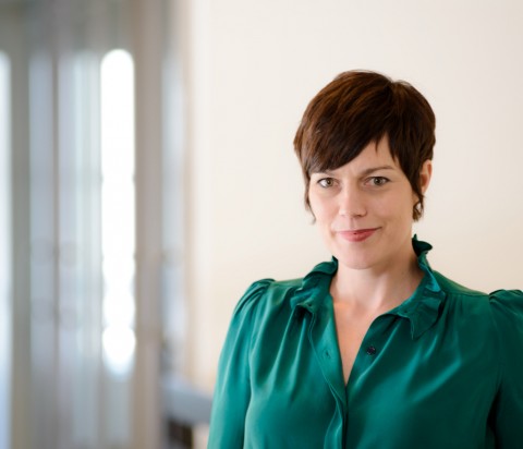 IMCO Director of Marketing, Ashley Kimberley Ashley Kimberley standing in natural light in office, wearing emrald green blouse.